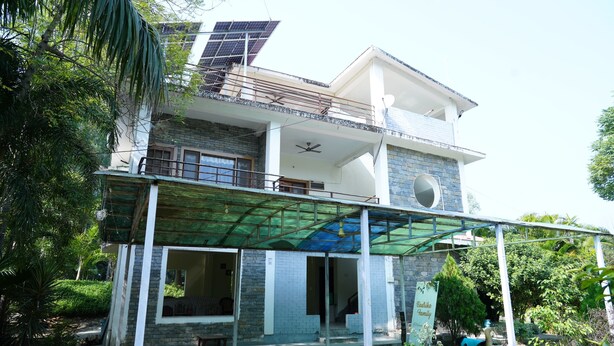 A two-story house with a balcony, solar panels, and a covered entrance. - Badrika Farm's (Huzur)