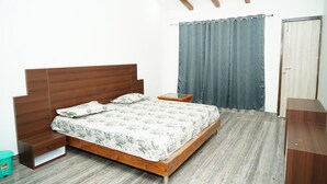 A bedroom with a wooden bed, a nightstand, a small table, a wardrobe, and a curtain. - Badrika Farm's (Huzur)