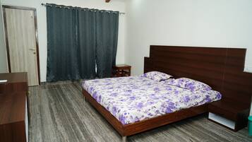 Ein Schlafzimmer mit einem hölzernen Bett, einem Nachttisch, einem Holzschrank und einem dunklen Vorhang.