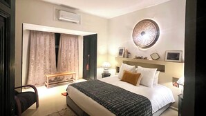 Une chambre d’hôtel avec un grand lit, une table de chevet avec une lampe, un miroir fixé au mur et un élément décoratif mural.