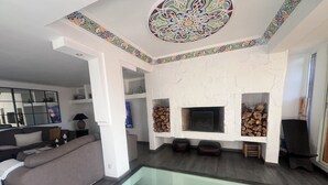 Un salon moderne doté d’une piscine à fond de verre, d’une cheminée et d’un grand miroir.