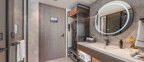 A modern bathroom with a large mirror, a sink, and a shower area.