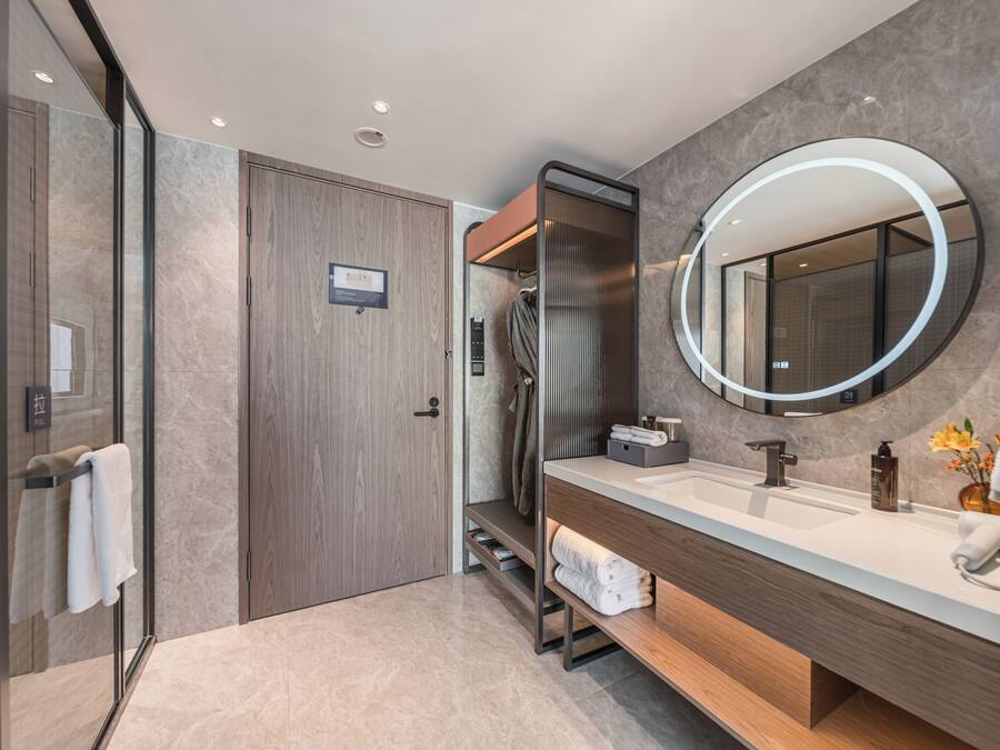 Un baño moderno con un espejo grande, un lavamanos y una zona de ducha.