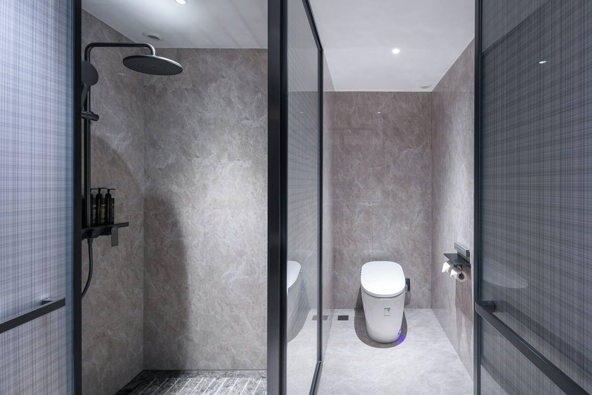 Un baño moderno con ducha, inodoro y mampara de vidrio.