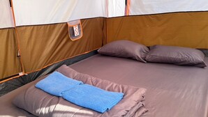 A tent with a bed inside, featuring a blue towel and two pillows. - Tent Room Koh Kood (Ko Kut)