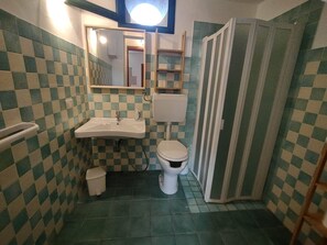 Een badkamer met een zwart-wit geruit tegelpatroon, een wastafel, een toilet en een douchehoek.
