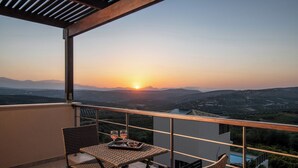 A balcony with a table and chairs, overlooking a scenic landscape during sunset. - Villa Plyto Amazing views Heated pool (Hersonissos)
