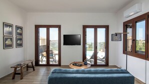 A modern living room with a sofa, a wooden bench, a tray with drinks, and a TV on the wall. - Villa Plyto Amazing views Heated pool (Hersonissos)