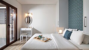 A modern bedroom with a bed, a desk, and a chair. There is a tray with food and drinks on the bed. - Villa Plyto Amazing views Heated pool (Hersonissos)