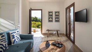 A modern living room with a blue sofa, a wooden coffee table with drinks, and a TV mounted on the wall. - Villa Plyto Amazing views Heated pool (Hersonissos)