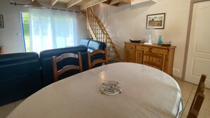 Ein Essbereich mit rundem Tisch, Stühlen, einer Holztreppe und Blick ins Freie.