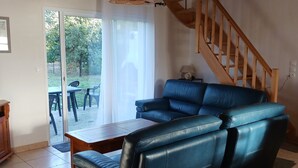 Ein Wohnzimmer mit einem blauen Ledersofa, einem Holztisch und einer Treppe.