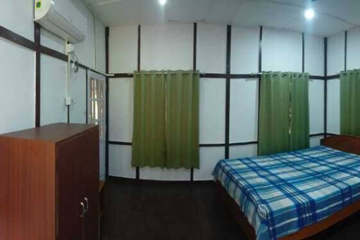A room with a bed, a wooden cabinet, and a small stool.