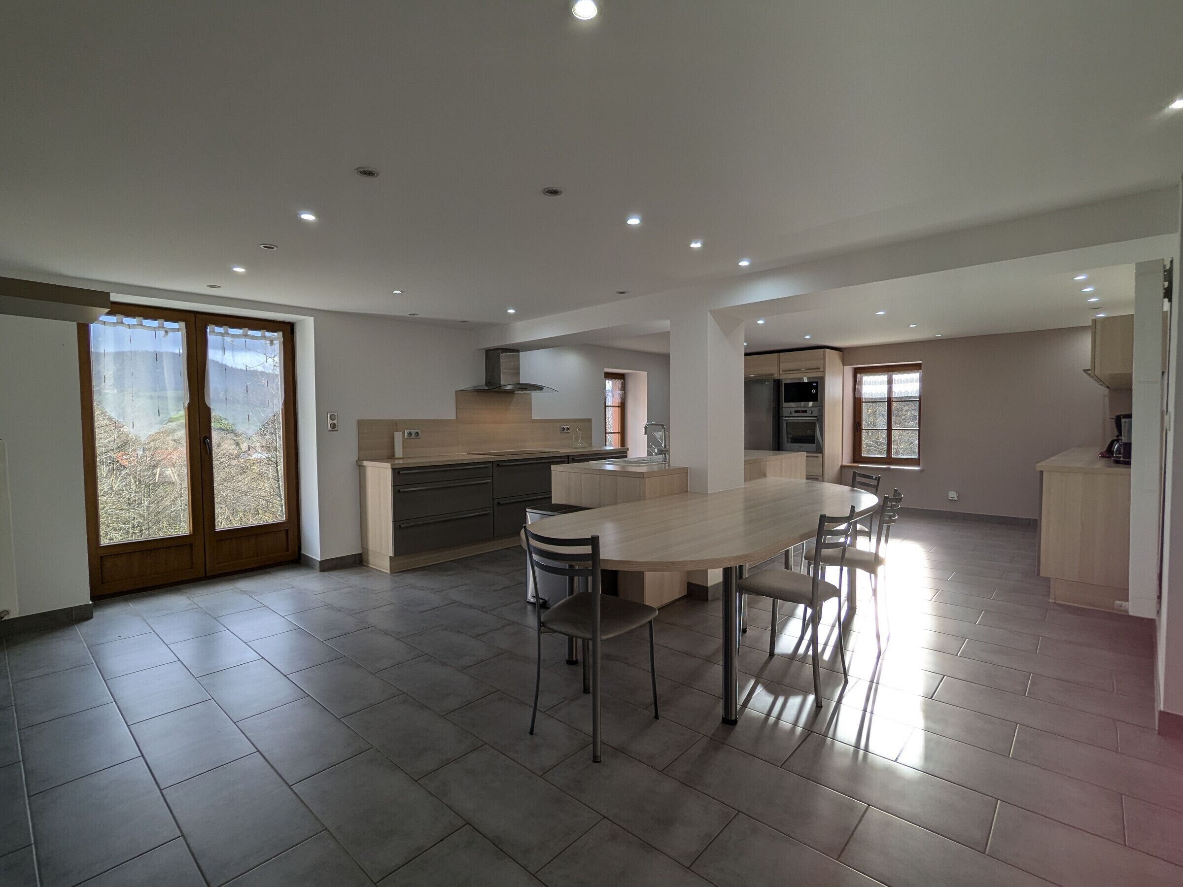 A modern kitchen with a central island, built-in appliances, and a dining area with chairs.