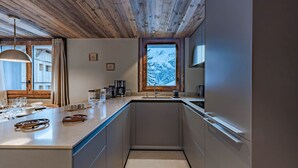 Una cocina moderna con techo de madera, un ventanal grande y vistas a montañas nevadas.
