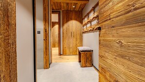 Un pasillo con paneles de madera, un banco y una puerta que da a otra habitación.
