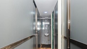 A modern hallway with a wooden floor and glass doors leading to a restroom. - Golden Sands Dormitory & Single AC Rooms (Mumbai)