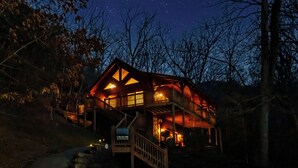 Une cabane avec un escalier menant à l’entrée, entourée d’arbres.