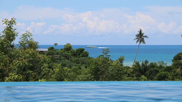 A pool with a view of the ocean and a boat in the distance.