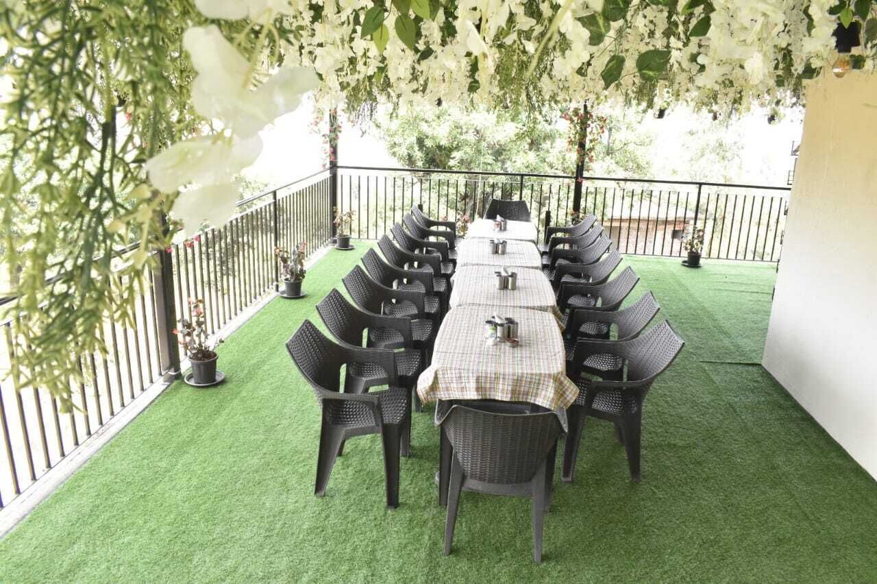 Un área de comedor al aire libre con una mesa larga y sillas, rodeada por una valla blanca y follaje.