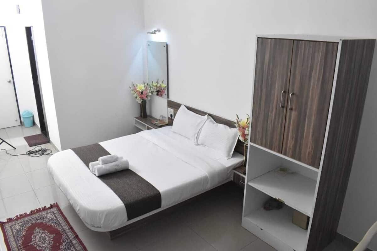 Un dormitorio moderno con cama, armario, mesita de noche con espejo y un jarrón con flores.