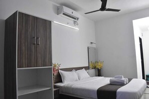 A modern hotel room with a large wardrobe, a bed with white linens, a ceiling fan, and an air conditioning unit. - Nature Nest Valley Resort (Mahabaleshwar)