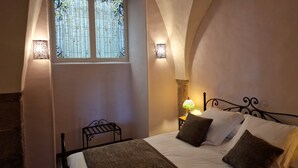 Een slaapkamer met een bed, een raam met een glas-in-lood ontwerp, en twee wandlampen.