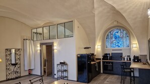 Een moderne keuken met een eethoek, voorzien van een groot raam met een glas-in-lood ontwerp, een inbouwoven en een koffieapparaat.