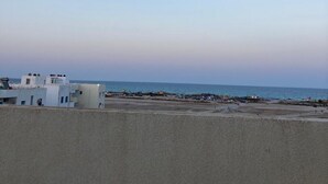 A coastal view with a clear sky, a sandy beach, and a few buildings in the distance. - Bagdadi region tourist area Mahdia sea view (Mahdia)
