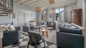 Een moderne woonkamer met een zwart-wit schakeerd vloer, twee banken, een salontafel en hangende rieten lampen.