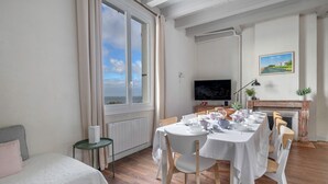 Een eetgedeelte met een tafel voor vier personen, een televisie en een open haard.