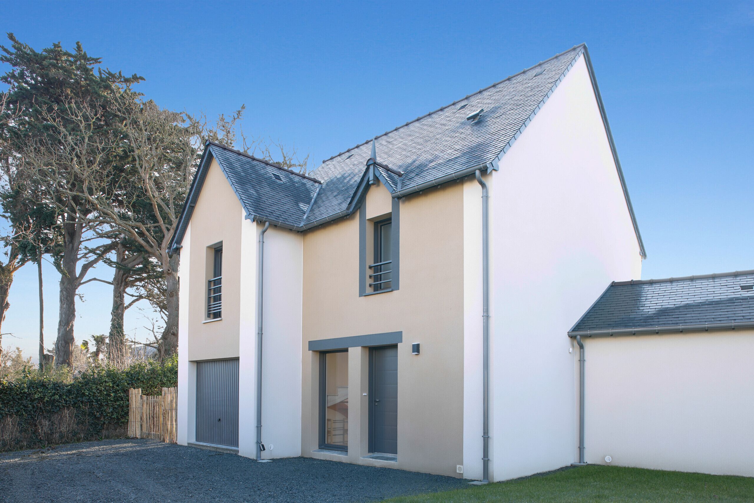 A modern two-story house with a sloped roof, a garage, and a small front yard.