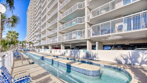 Un hotel con piscina, varios balcones y un estacionamiento.