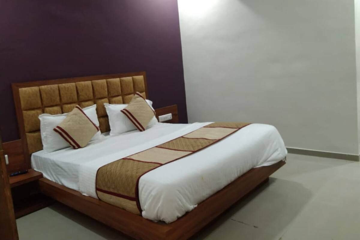 Una cama bien hecha con cabecera de madera y cubrecama estampado.