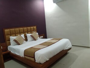 Uma cama bem arrumada com cabeceira de madeira e colcha estampada.