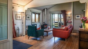 Een gezellige woonkamer met een open haard, houten vloeren en een groene fauteuil.