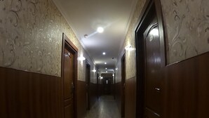 A long, narrow hallway with wooden doors and walls, leading to a dark room at the end. - Hotel Noor Empire International (Bengaluru)