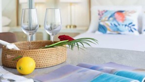 Et hotelværelse med en seng, et natbord med to glas og en kurv, samt en pude med blomstermønster.