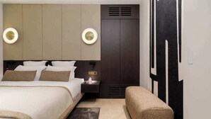 Une chambre d’hôtel moderne avec un grand lit, des tables de chevet, un banc et une armoire.