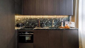 Une cuisine moderne avec des meubles de couleur sombre, un plan de travail en marbre et des appareils électroménagers intégrés.