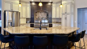 Una cocina moderna con una isla grande, electrodomésticos de acero inoxidable e iluminación colgante.