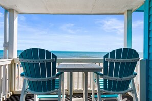 Un espace extérieur abrité, avec deux chaises et une table, donnant sur la plage.