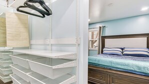 A bedroom with a bed, a nightstand, and a white shelving unit with baskets. - 6 Mi to Spectrum Center: Spacious Getaway w/ Deck (Charlotte)