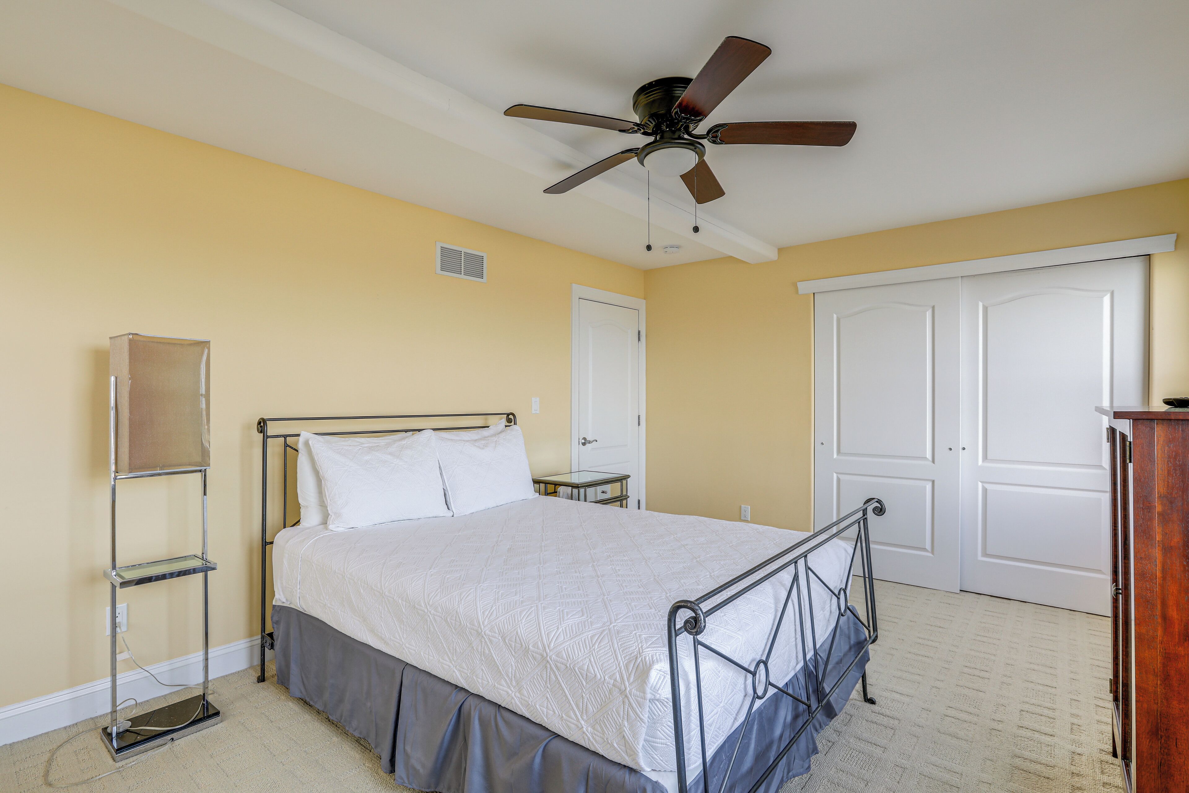 A bedroom with a bed, a ceiling fan, a wardrobe, and a bedside table.