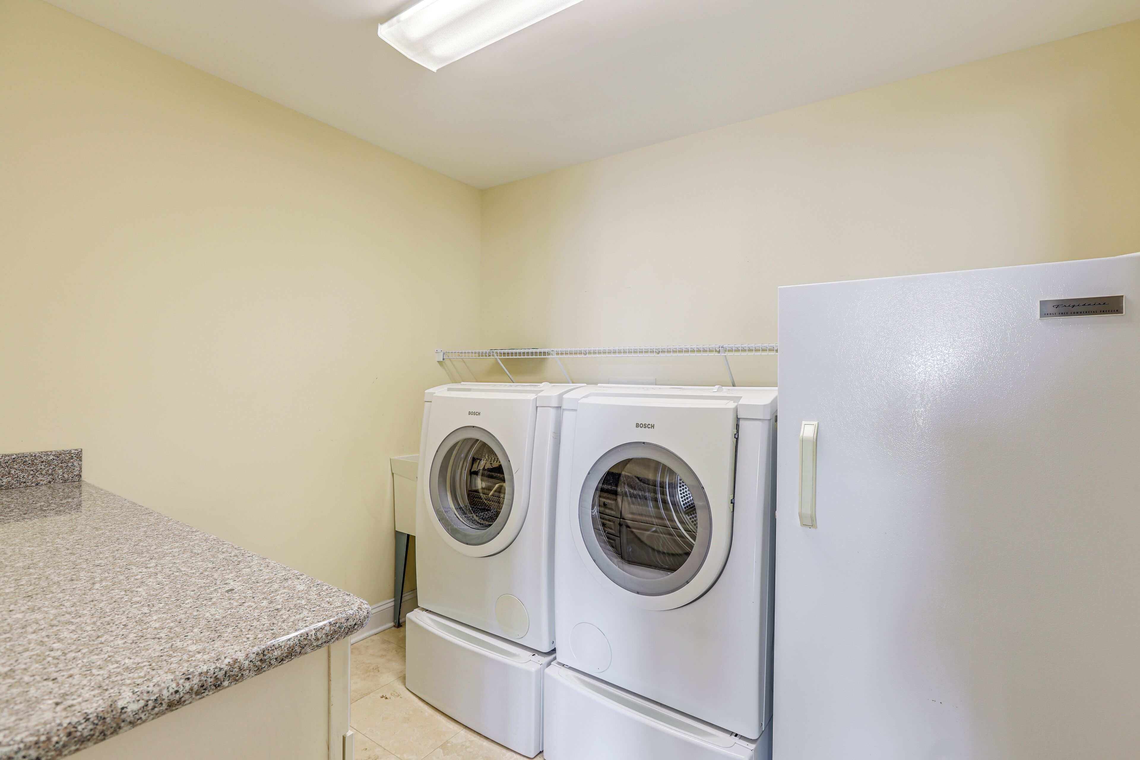 A laundry room with two Bosch front-loading washing machines and a white refrigerator.