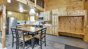 Une cabane en bois comprenant un coin repas, une cuisine et une terrasse supérieure.