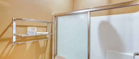 A bathroom with a glass shower enclosure, a towel rack, and a toilet.
