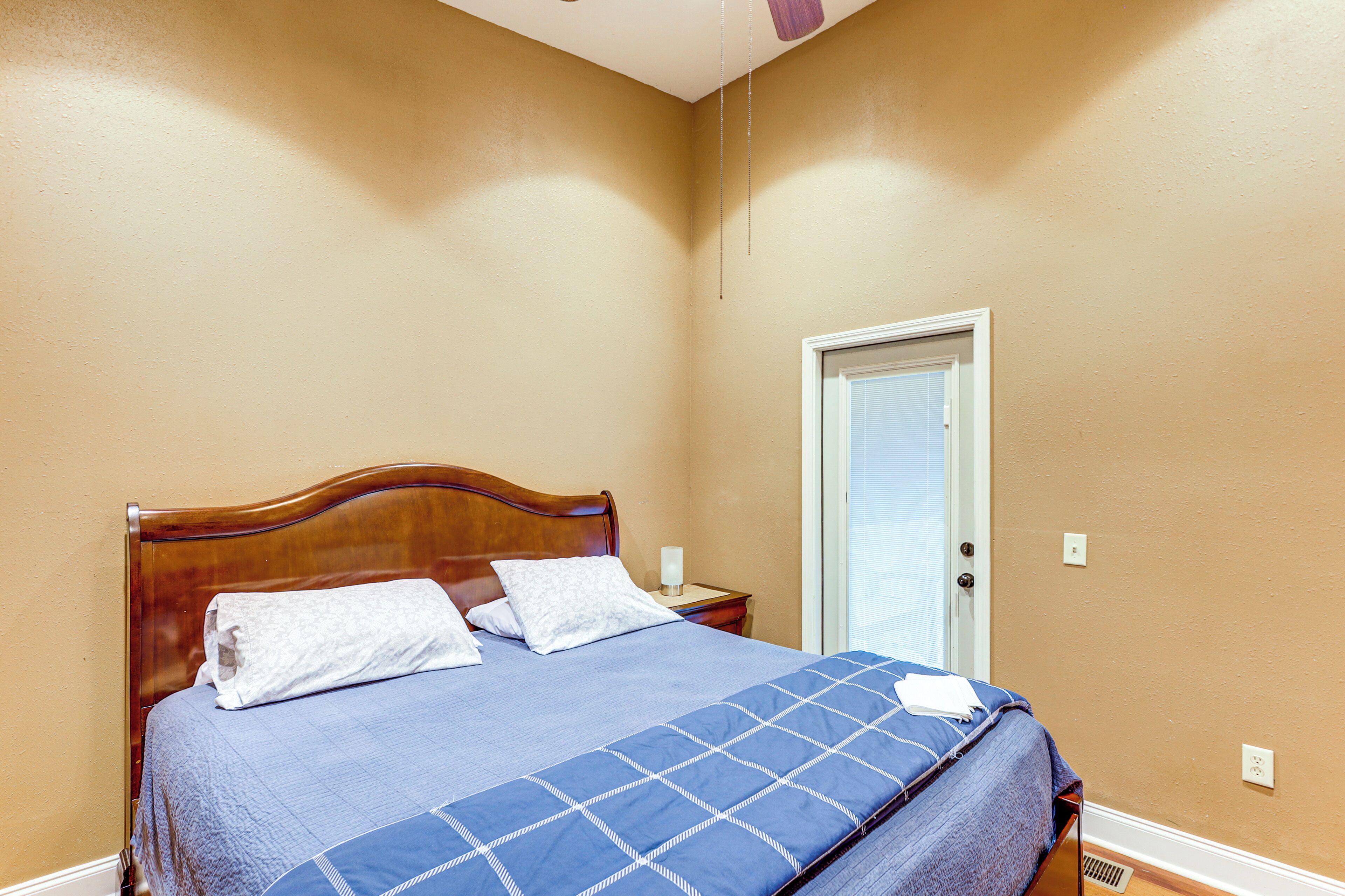 Un dormitorio con cama de madera, colcha azul y puerta blanca.