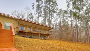 Una casa a due piani con un portico e una tettoia, immersa in una foresta.