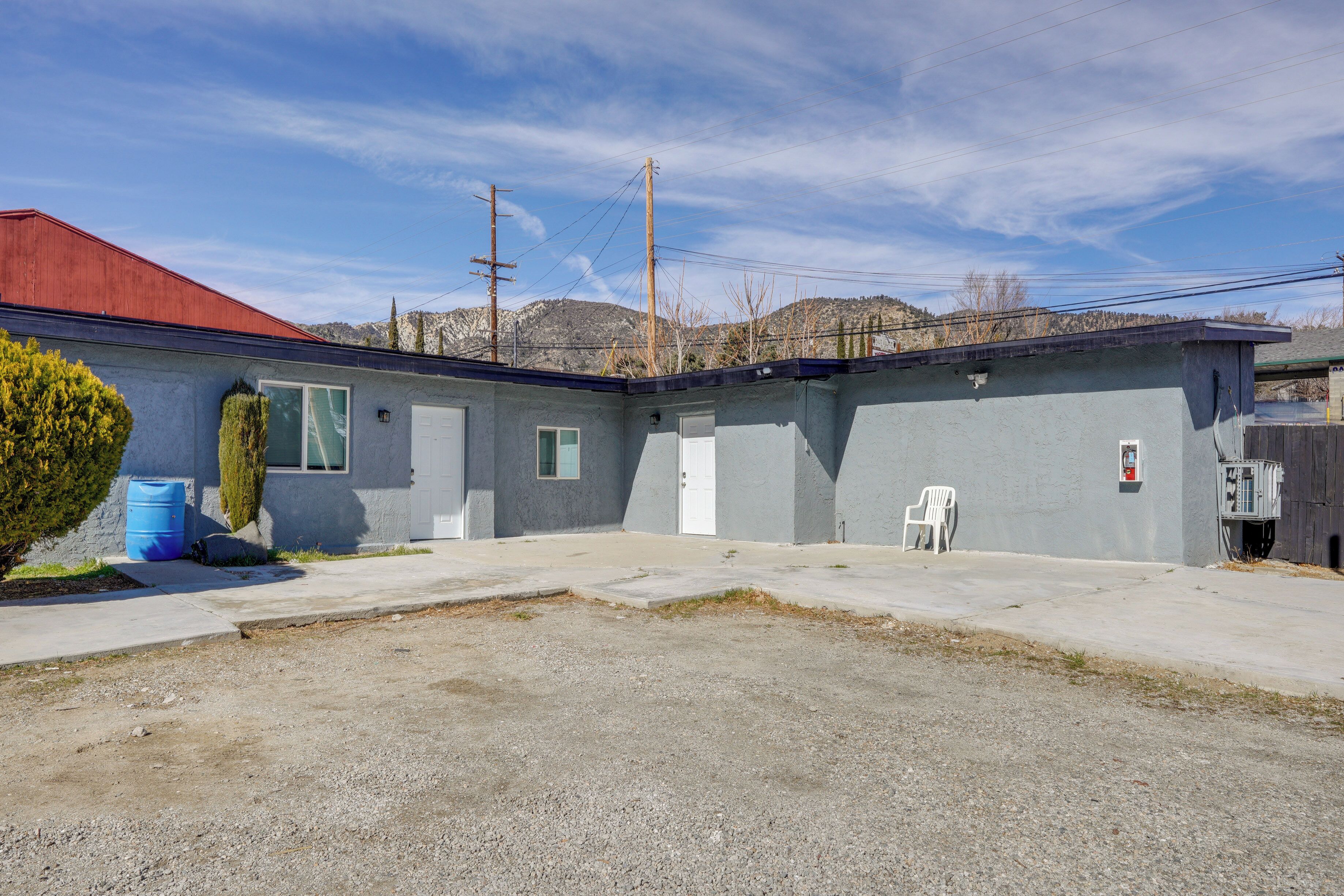A two-story motel with a red roof, a gravel driveway, and a small parking area.